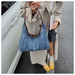 Detail of blue denim tote bag with leather handle and magnetic snap button closure