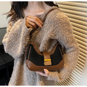 Detail of suede half-moon bag with gold metal buckle and two-tone stitching finish