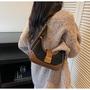 Detail of color-block suede hobo bag with gold buckle and chain strap on shoulder