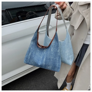 Detail of blue denim tote bags with vintage snow wash finish and brown leather straps