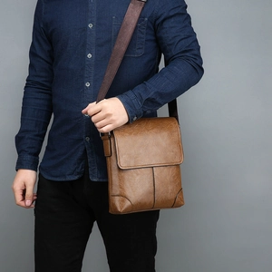 Detail of brown leather business crossbody bag with wide shoulder strap and flap closure