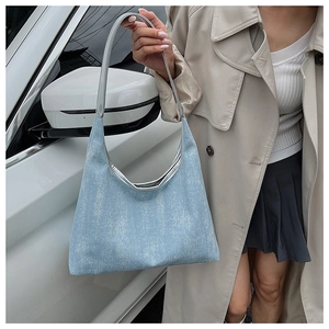 Detail of light blue denim tote with silver metallic handle and textured trim