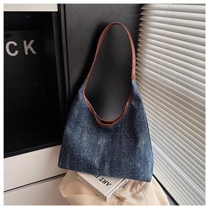 Detail of blue denim canvas tote bag with brown leather straps and vintage contrast finish
