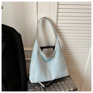 Detail of light blue hobo bag with shimmering fabric on a silver suitcase