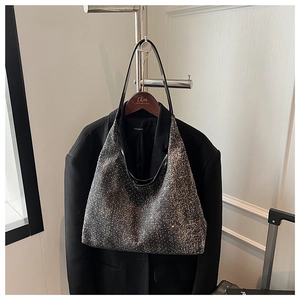 Detail of silver sequin hobo bag with black leather strap on a black blazer