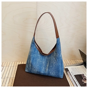 Detailed view of deep blue denim hobo bag with sparkling crystals and brown leather strap