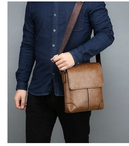Close-up of brown vintage leather crossbody bag with wide strap and pebble texture