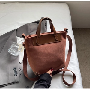 Detail of vintage brown suede tote bag with leather handles and textile shoulder strap