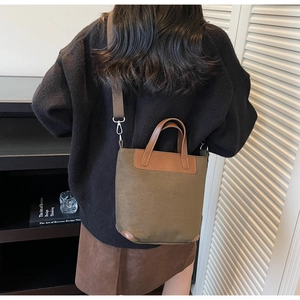 Detail view of brown-green canvas tote bag with leather trim and wide shoulder strap