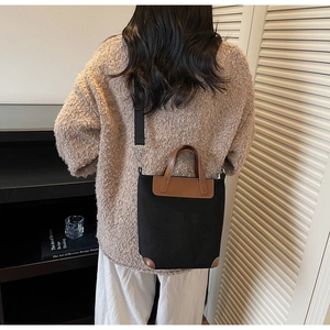 Detail of retro tote bag showing black canvas and brown leather trim on female model