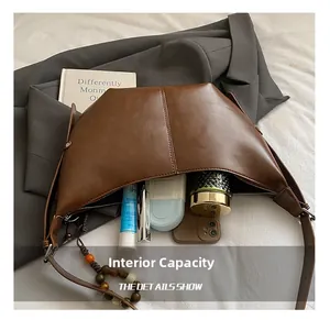 Détail montrant la capacité interne du sac hobo marron avec cosmétiques et mobile