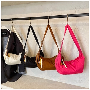 Borse a tracolla in nylon bianco, nero, marrone e rosa con ciondoli su un supporto