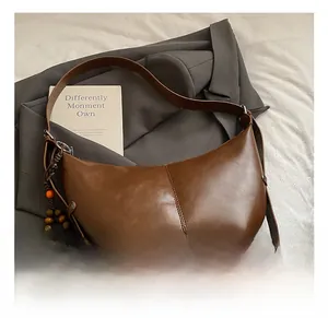 Détail du sac hobo en cuir marron foncé avec couture centrale et perle en bois décorative