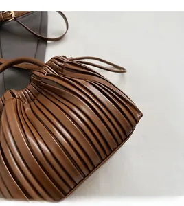 Close-up of brown pleated handbag showing soft glossy leather texture and vertical pleats