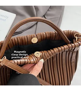 Detail of magnetic snap closure and pleated texture on brown leather handbag