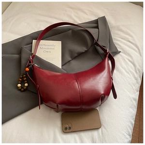 Détail du sac bandoulière demi-lune bordeaux avec perles vintage sur un blazer gris