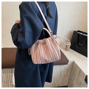 Detail of light pink pleated handbag featuring soft leather texture and adjustable strap