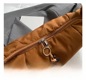Dettaglio borsa a tracolla in nylon caramello con zip argento e ciondolo con perline