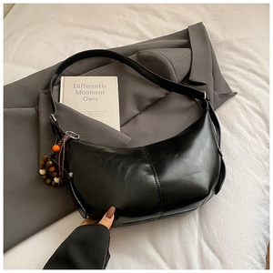 Détail du sac hobo demi-lune en cuir brillant noir avec breloque décorative en bois