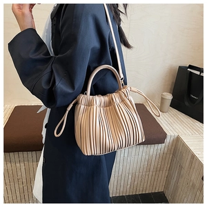 Detail of soft pleated beige leather handbag with vertical textures and slim shoulder strap