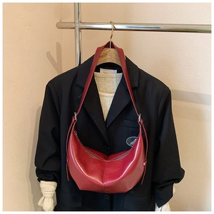 Détail du sac hobo en cuir rouge brillant suspendu à un blazer pour un style chic
