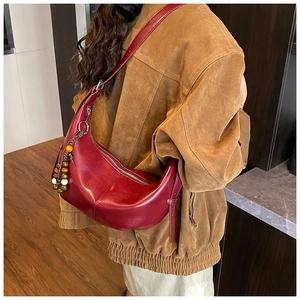 Détail du sac demi-lune bordeaux avec pendentif en perles rétro sur manteau en daim