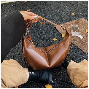 Détail d'un sac cabas géométrique en cuir marron avec pendentif en perles et sangle