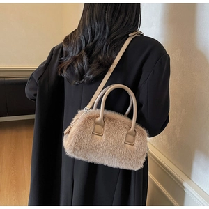 Back view of model carrying a khaki faux fur pillow bag with leather handles and strap