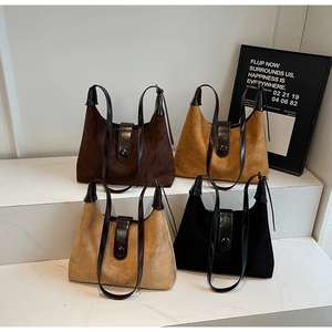 Detail showing four colors of vintage suede shoulder bags on a marble pedestal
