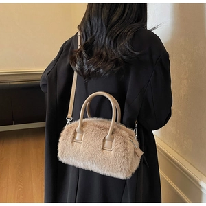 Close-up of beige plush pillow bag with faux leather handles and silver hardware detail