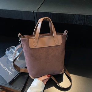 Vintage dark brown suede handbag with leather handles and detachable strap on a desk