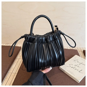 Detail of black pleated soft leather handbag with golden hardware and top handle