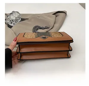 Detail of snake pattern flap and dark silver metal turn-lock on the chain crossbody bag