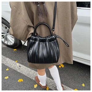 Detail of black pleated faux leather handbag featuring a unique accordion-fold texture