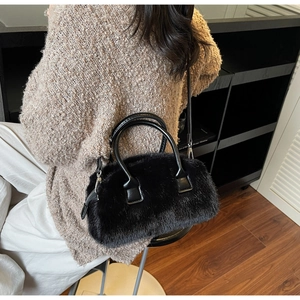 Detail shot of a black faux fur pillow bag worn by a model in a modern indoor setting