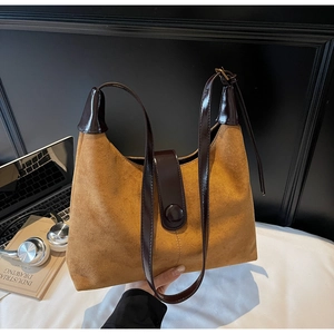 Close-up of vintage brown suede shoulder bag with dark leather straps in a lifestyle setting