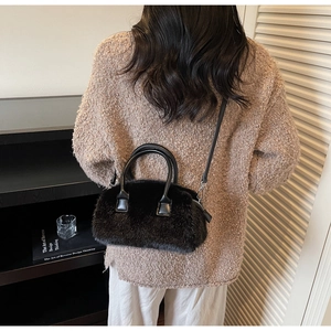 Detail of black faux fur pillow bag with leather handles and detachable shoulder strap