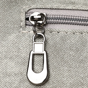 Close-up of industrial silver zipper and grey textured soft leather on a retro handbag