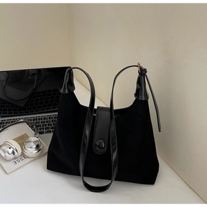 Detail view of black vintage high-quality tote bag styled with office laptop and headset
