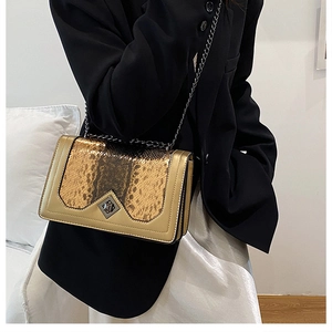 Detailed view of the gold crossbody bag with snakeskin texture and metal chain strap