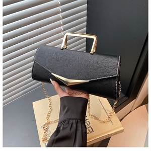 Detail of black lychee grain leather handbag with gold metal handle and chain strap