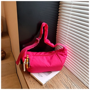 Dettaglio borsa a mezzaluna in nylon fucsia con ciondolo in perle di legno su legno