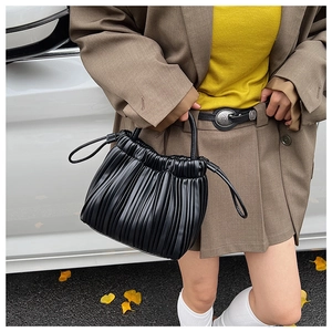 Detail of a black pleated handbag featuring dense vertical accordion folds and drawstrings