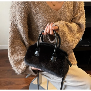 Detail of black plush pillow bag with soft faux fur texture and leather handles