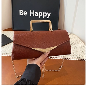 Detail of brown lychee leather handbag with gold V-hardware and metal square handle