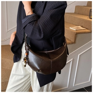Sac demi-lune en similicuir marron avec breloque en perles de bois porté par un mannequin