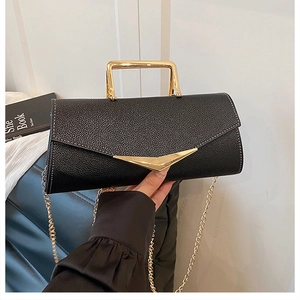 Detail of black lychee grain leather handbag with gold V-shape buckle and chain strap