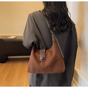 Detail of dark brown suede hobo bag featuring vintage buckle and smooth leather shoulder strap