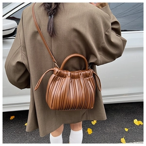 Close-up of brown pleated leather handbag styled with an autumn outfit on the street