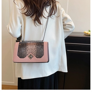 Detail of pink leather crossbody bag with snake skin texture and metal chain strap